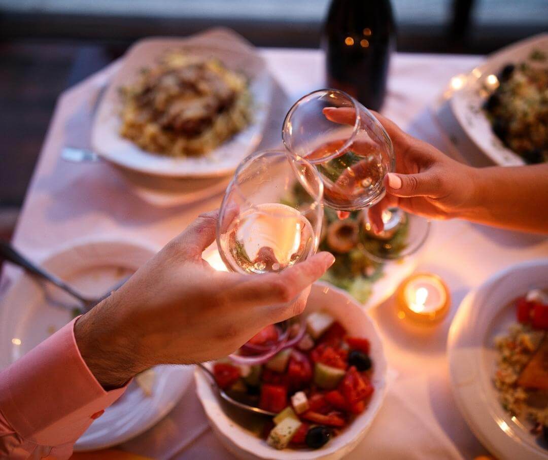 two people toasting with wine over dinner