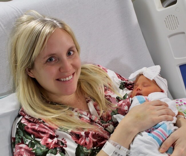 Mom holding her newborn baby and smiling in hospital bed