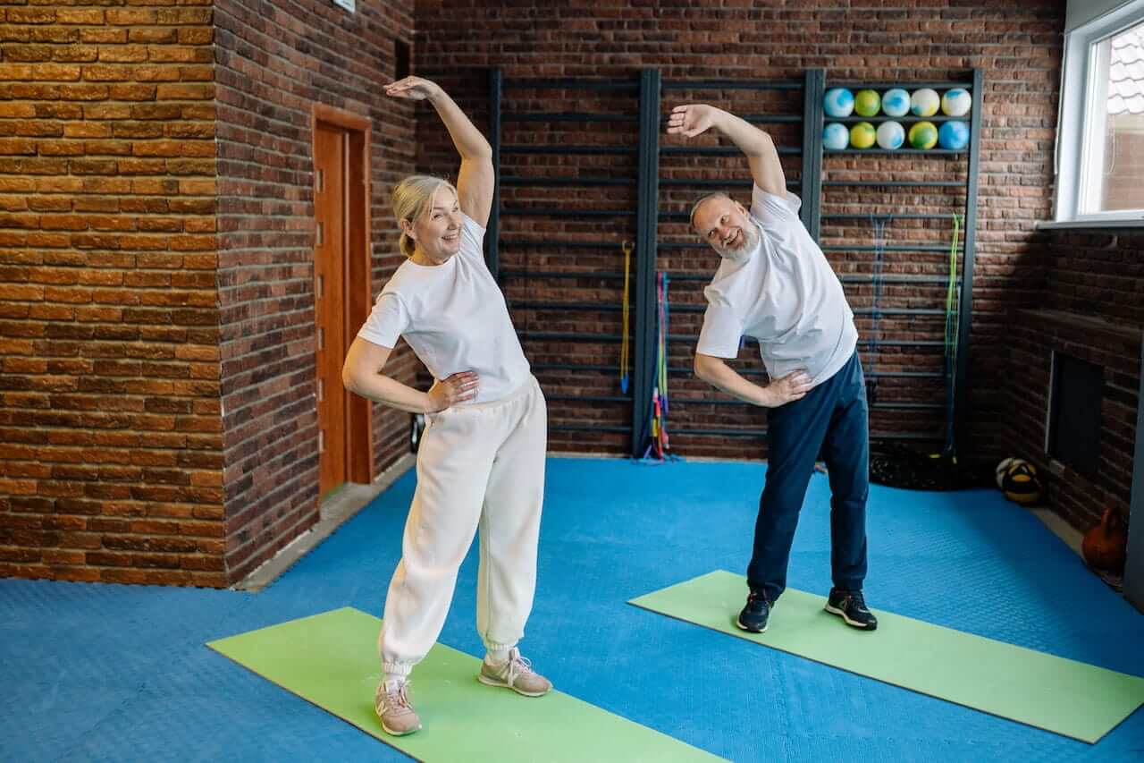 Elderly-couple-smiling-and-working-out-together-at-gym