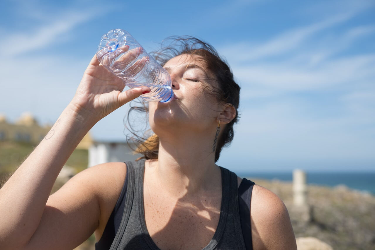 Woman-drinking-water-outdoors-after-workout