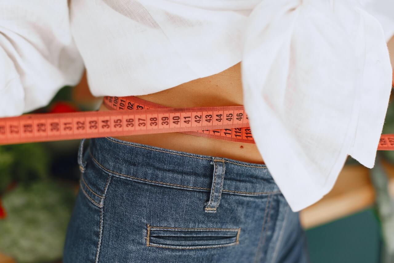 woman-using-metric-tape-to-measure-her-waist