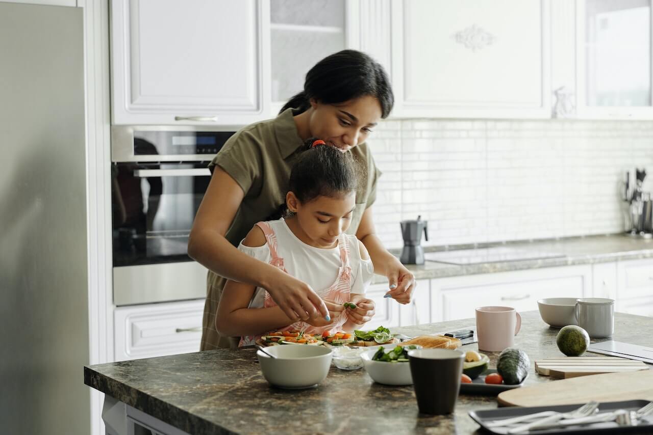 Woman-and-her-daughter-cooking-healthy-meal-in-home-kitchen