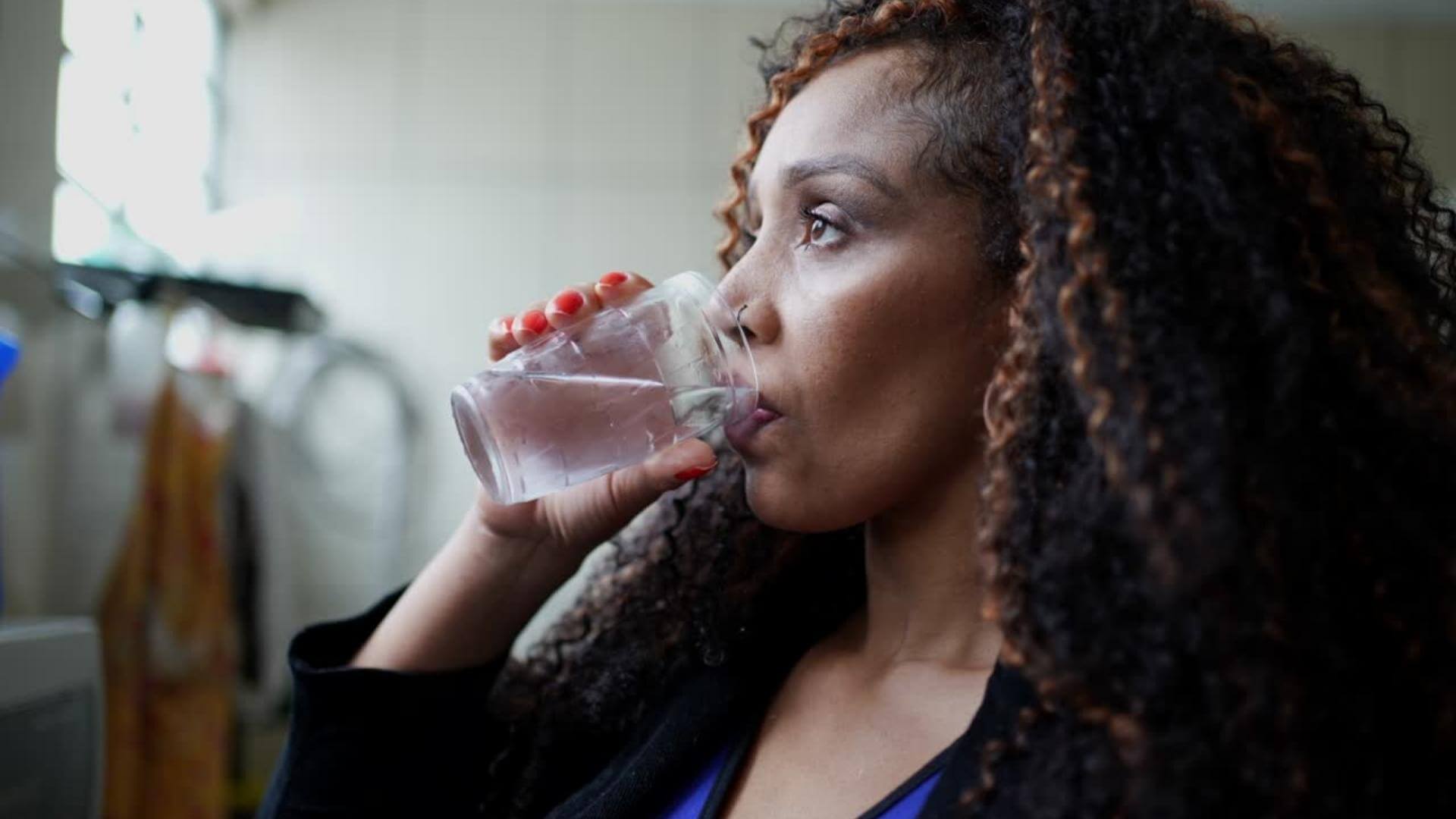 Woman drinking a glass of water in her kitchen