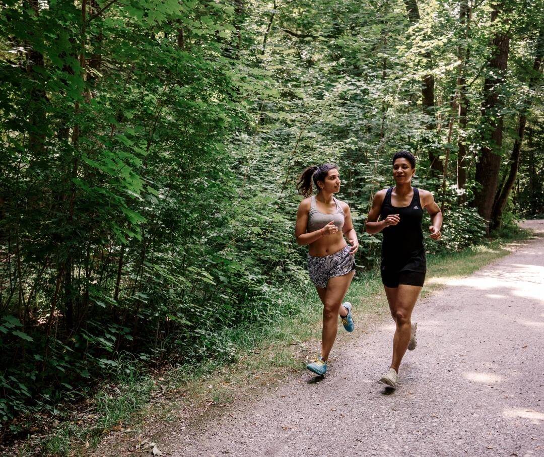 a couple jogging on a path through a wooded park