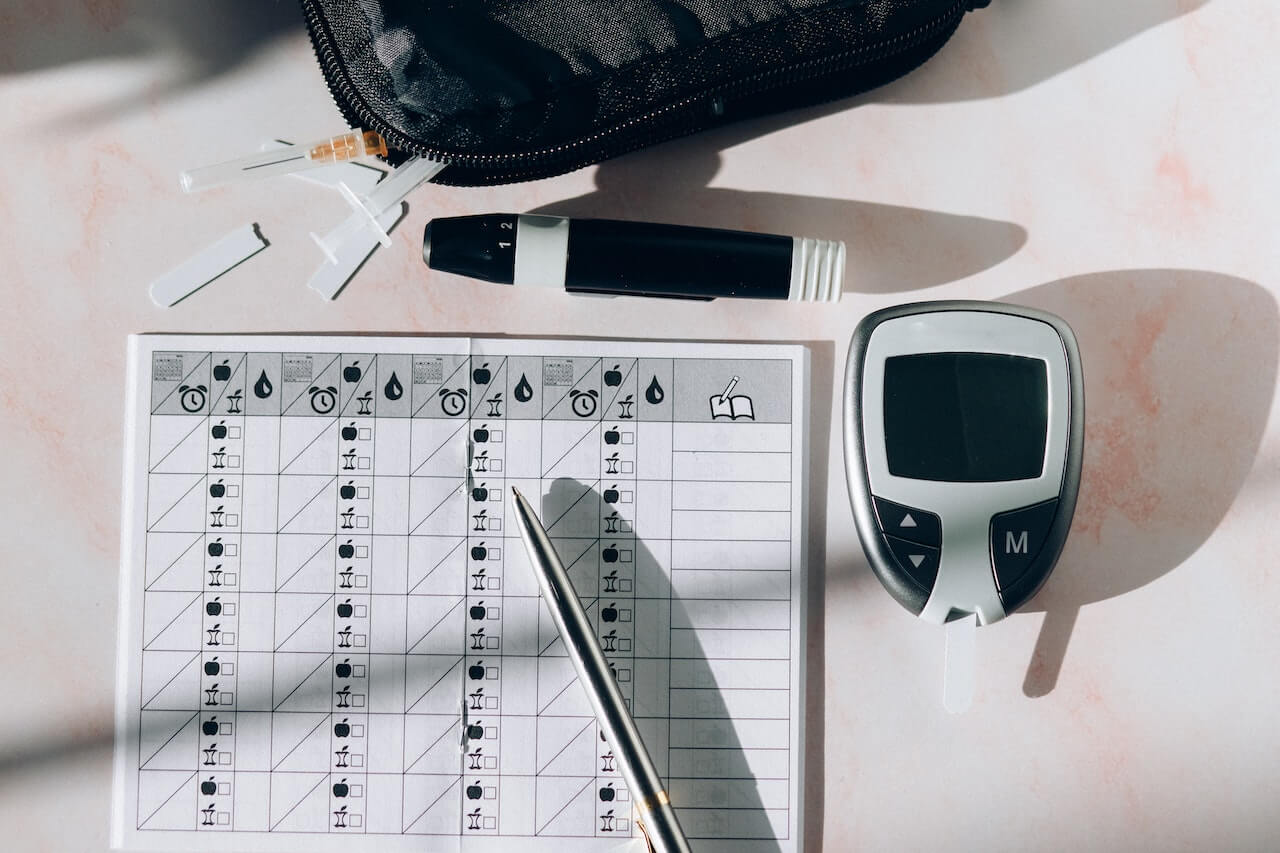 glucose-meter-with-test-kit-at-table-with-pen-and-paper