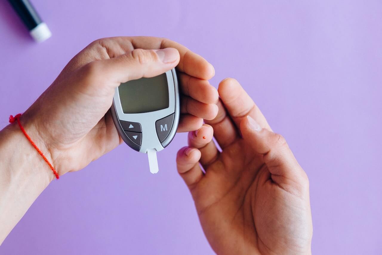 Man holding a glucose meter on purple background