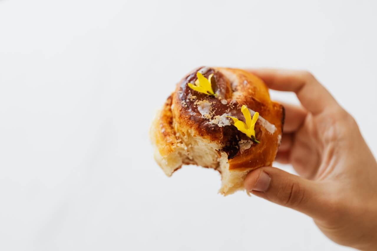 Close-up-of-hand-grabbing-cinnamon-roll