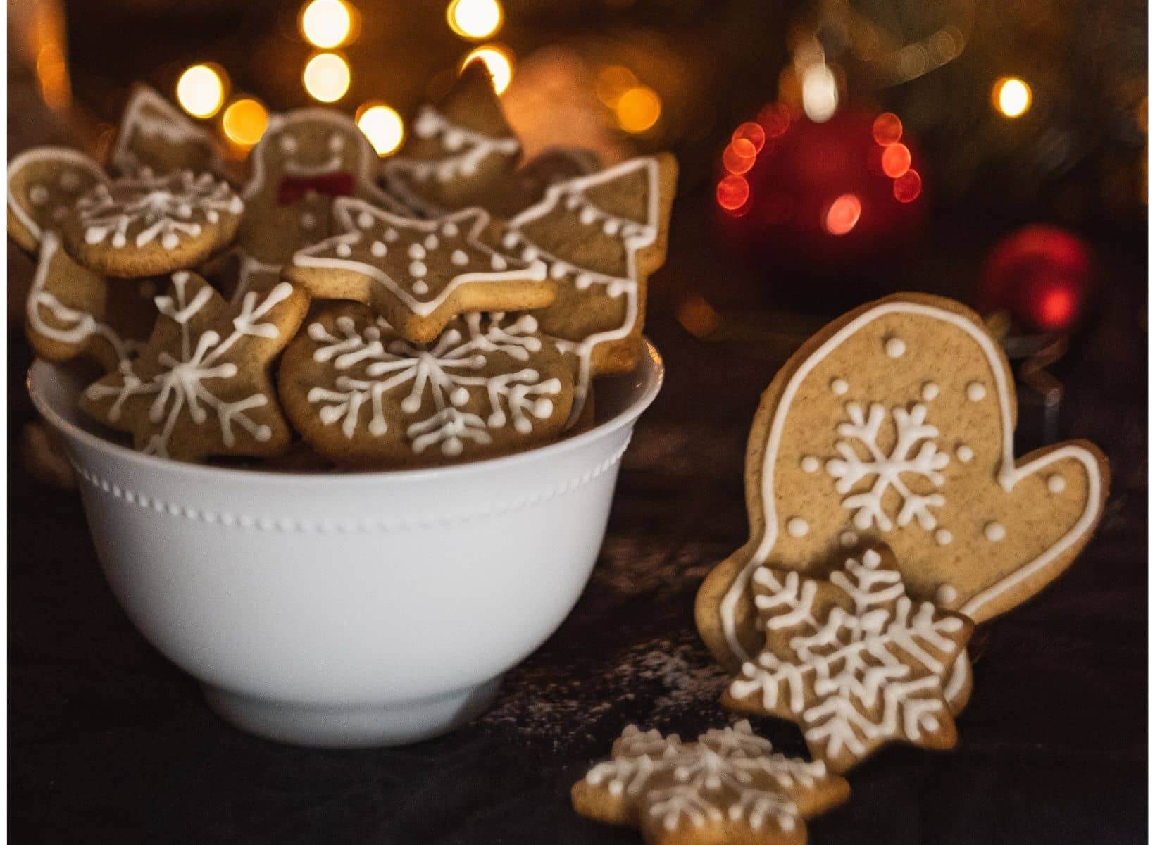 A close up shot of a white bowl of gingerbread cookies decorated with white icing