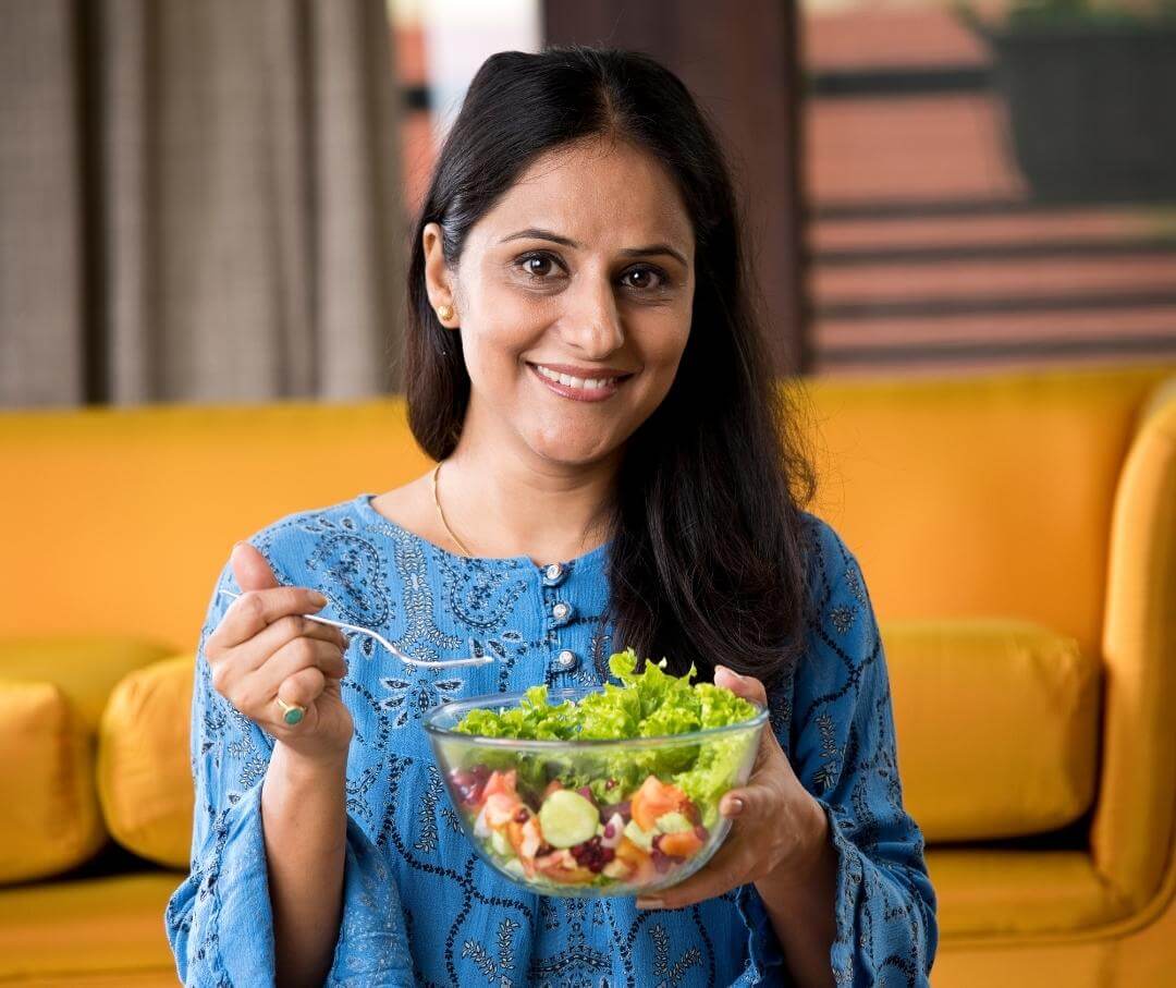 smiling woman holding a bowl of vegetable salad