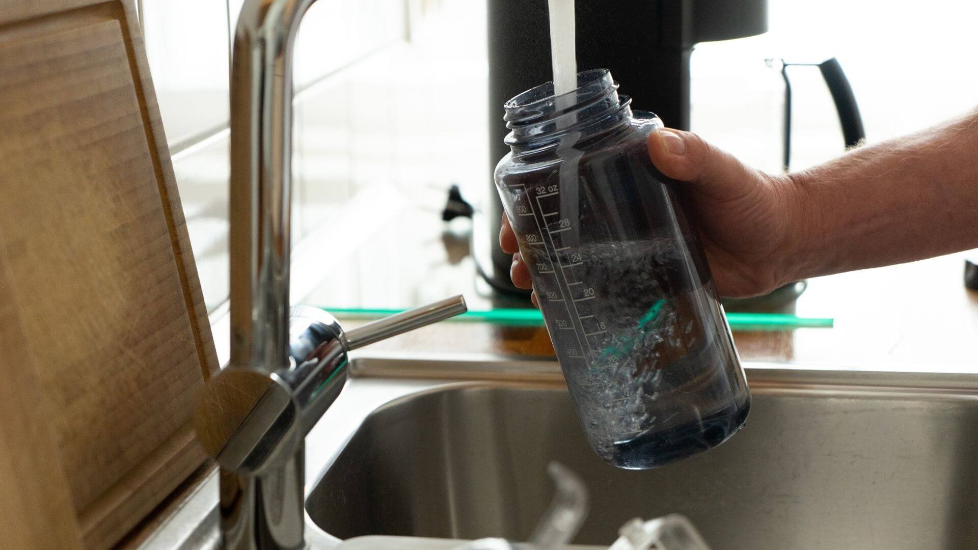 Man filling up reusable water bottle with faucet water