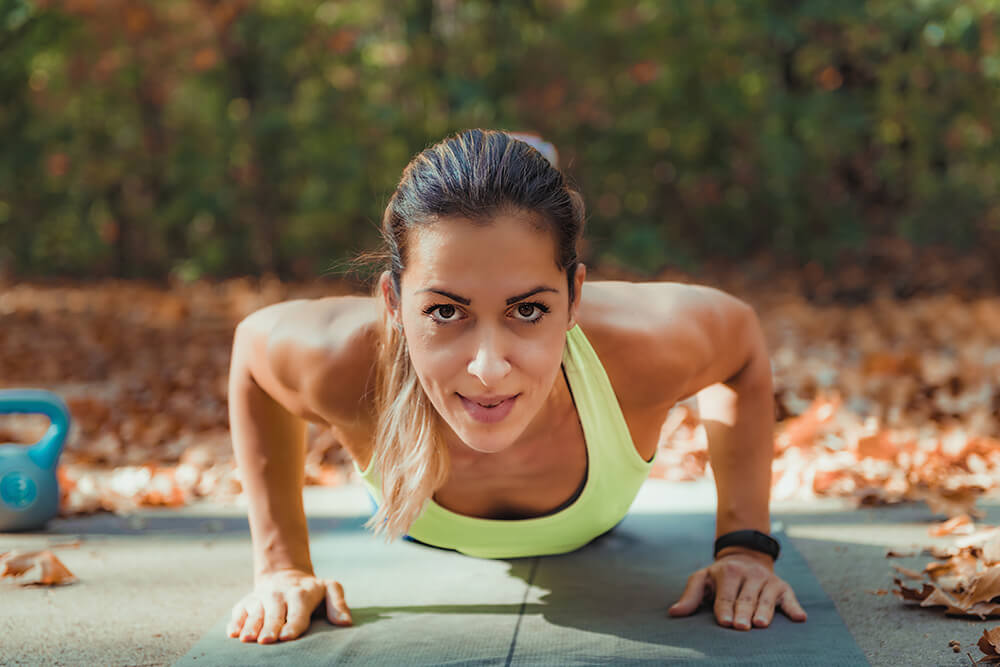 A woman outside doing a pushup