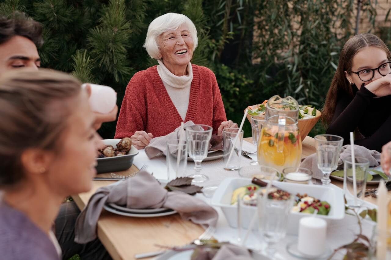 Elderly-woman-laughing-while-eating-healthy-lunch-with-family