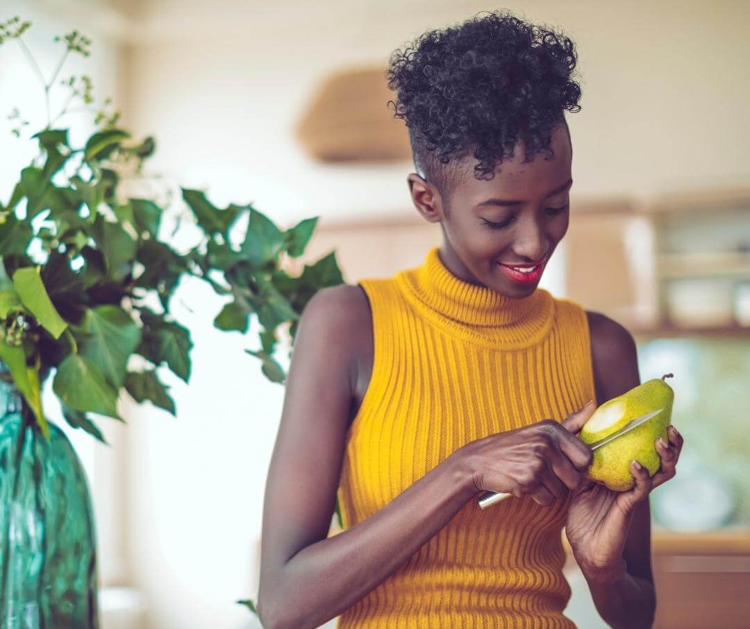 a woman cutting into a pear in her living room