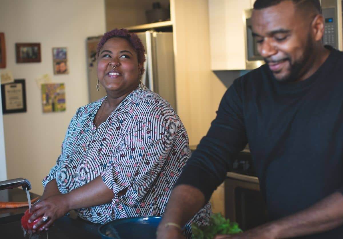 A Black couple cooking in the kitchen together