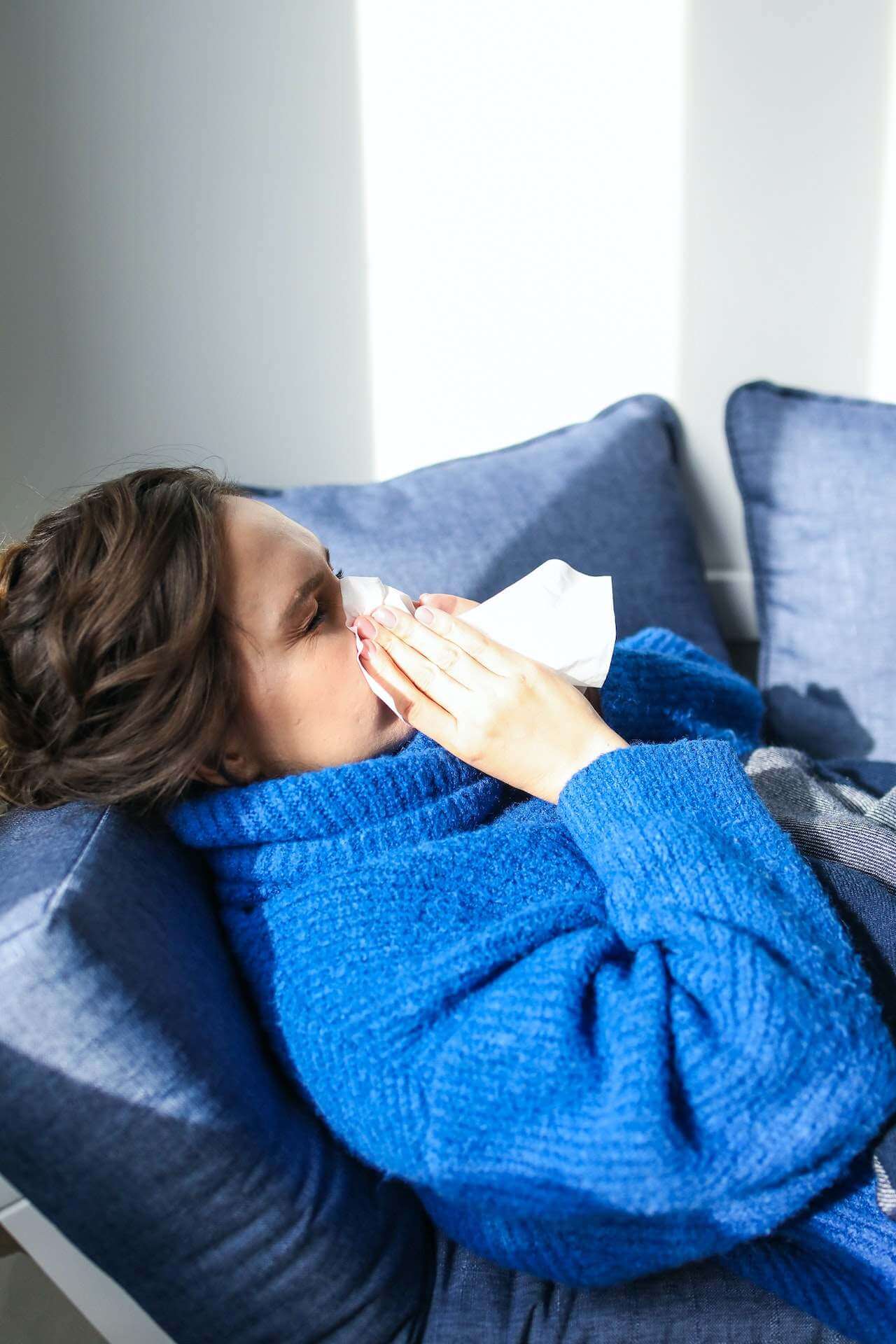 woman-sick-laying-in-her-couch-blowing-nose.jpg