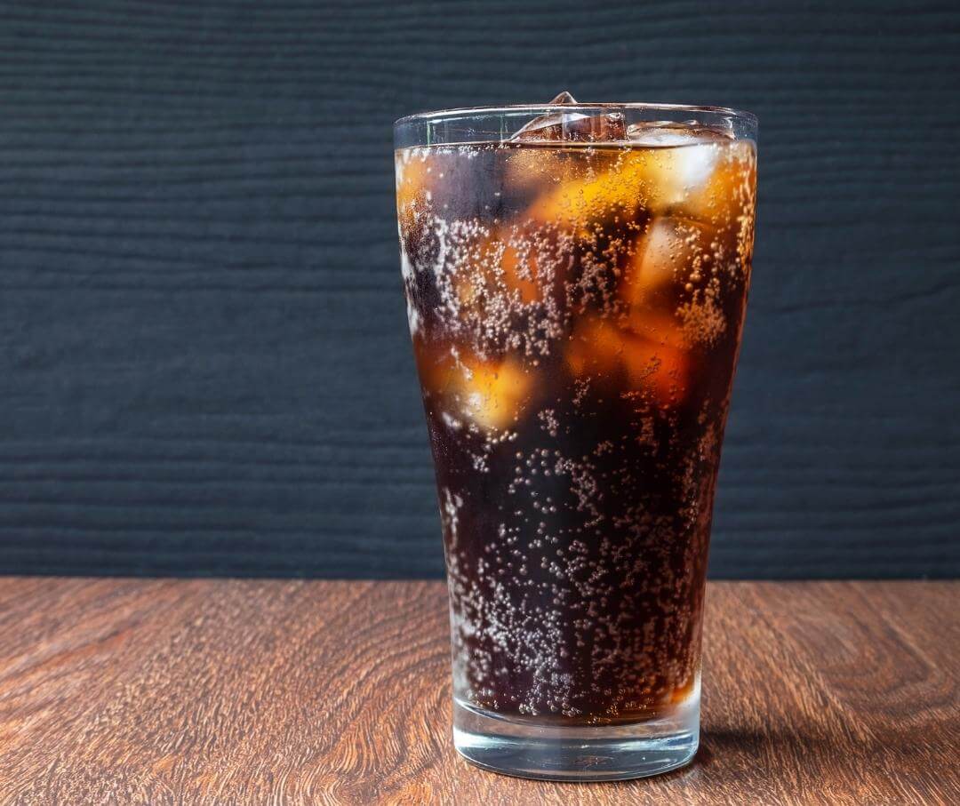 glass of diet cola with ice cubes on a wooden table