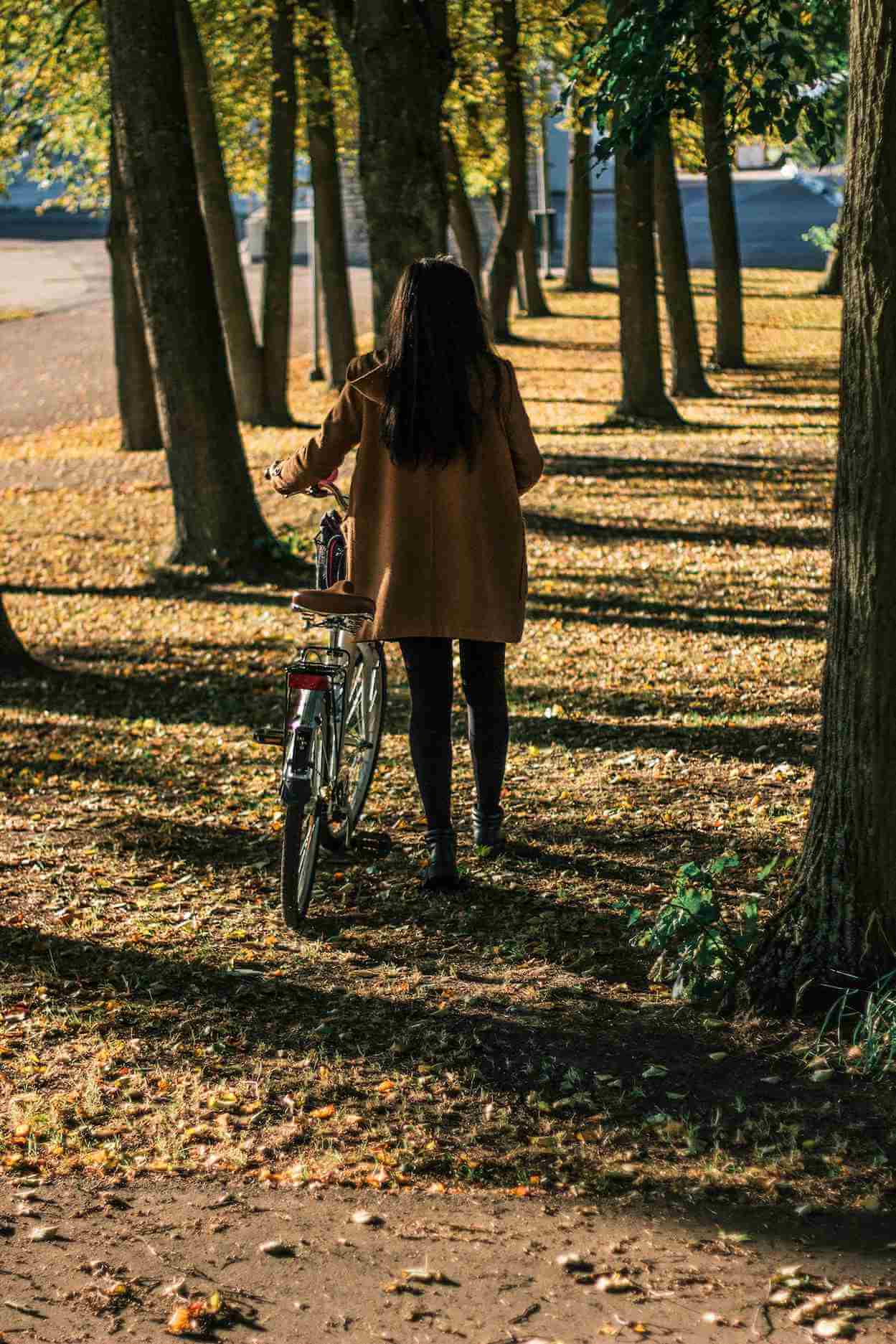 Woman walking next to her bicycle in the forest