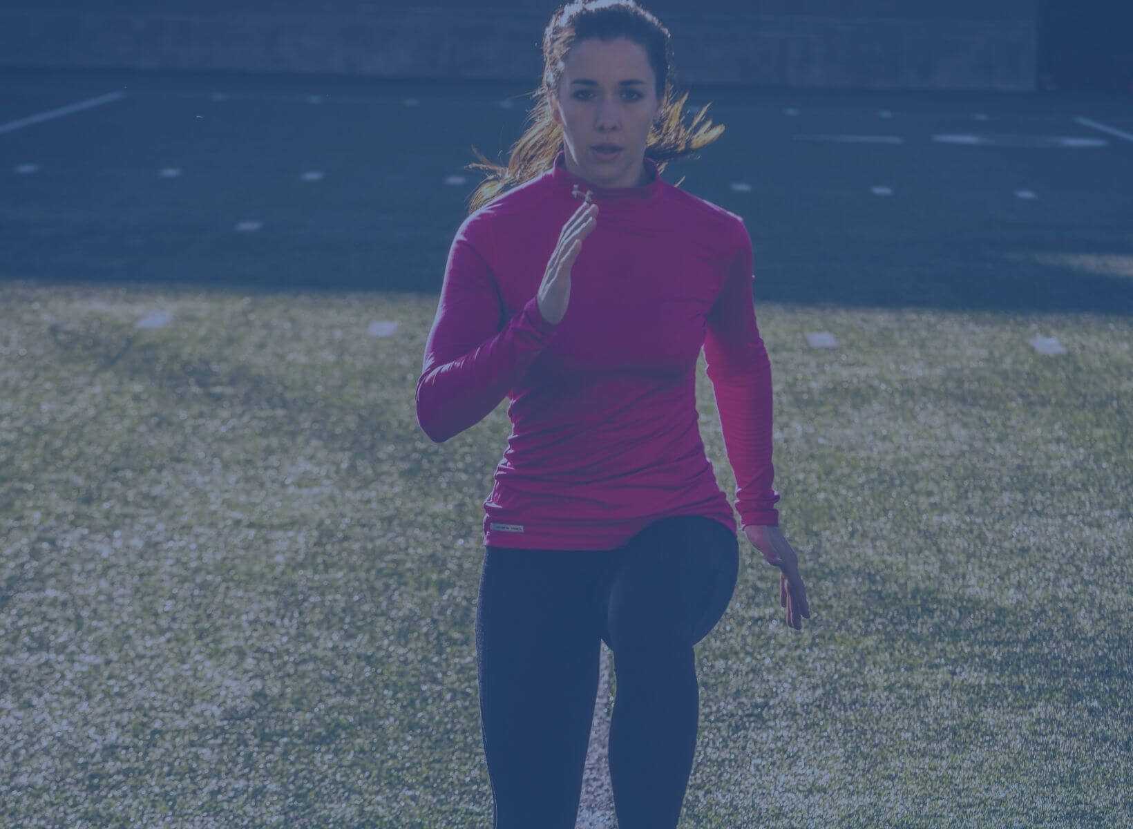 woman doing high knees on a grass field