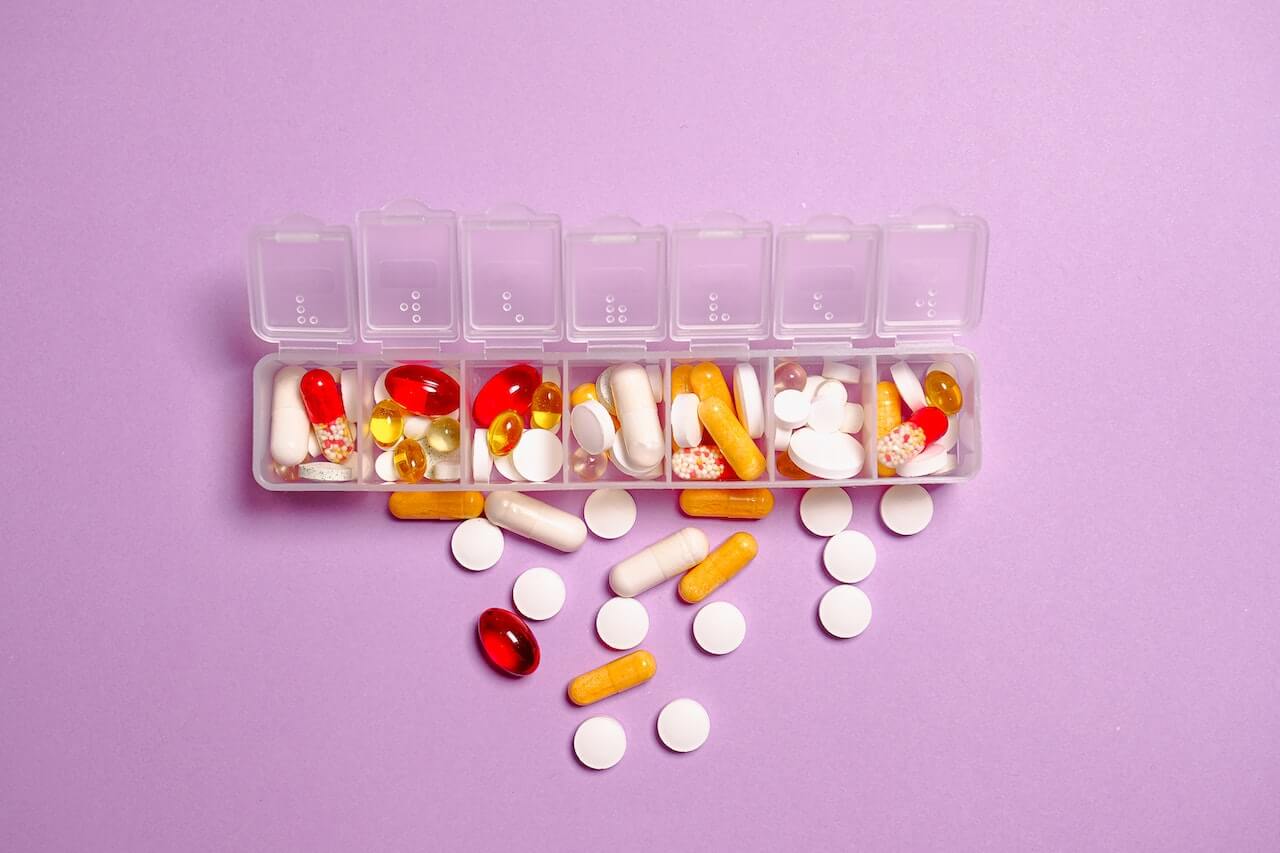 colorful-pills-on-pill-box-on-purple-surface