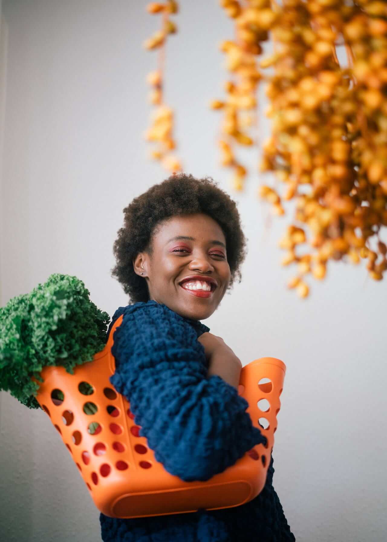 Happy-black-woman-holding-basket-with-lettuce-on-shoulder