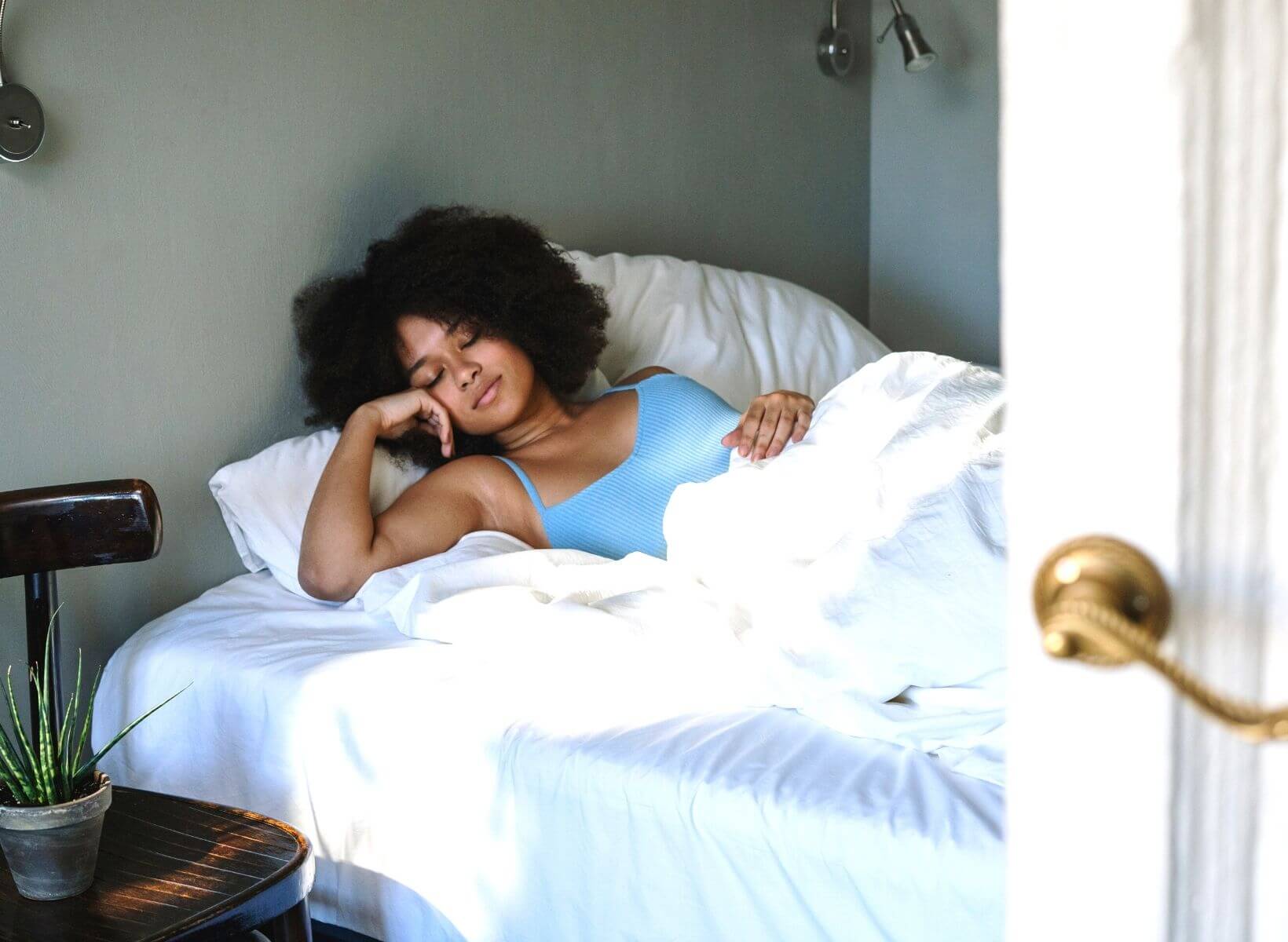 A woman sleeping in a bed with white sheets