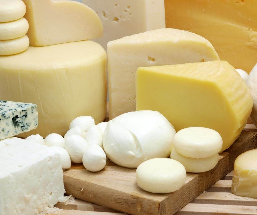 a variety of cheeses on a wood table