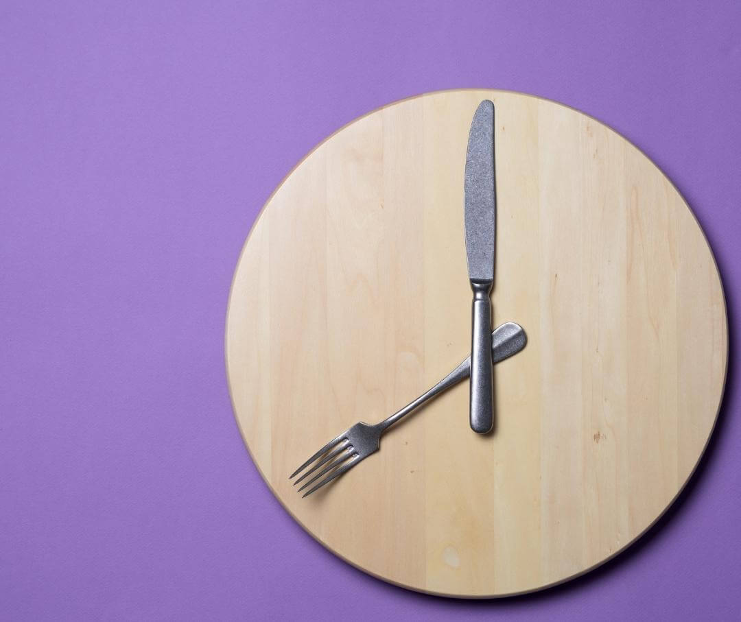 round wooden plate with fork and knife arranged like hands of a clock