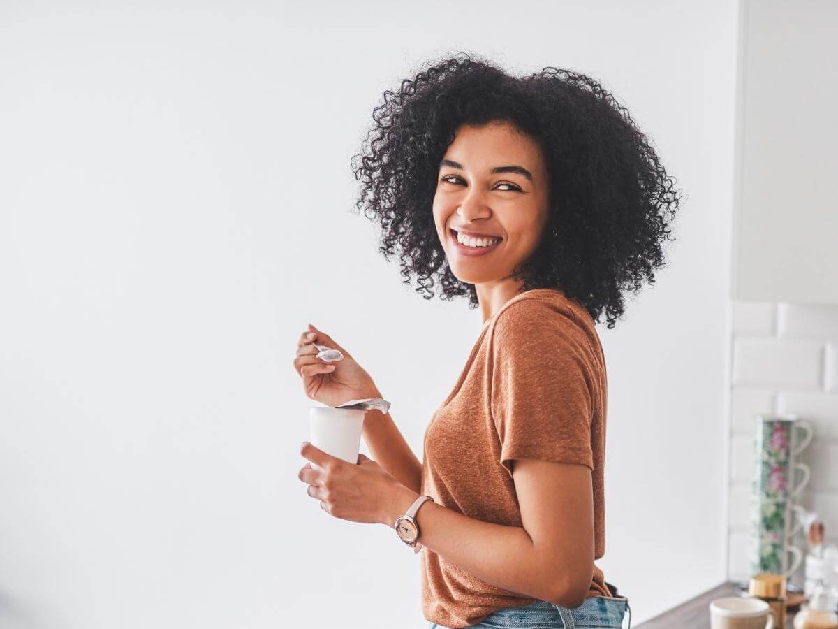 Happy woman eating probiotic-rich yogurt in her kitchen