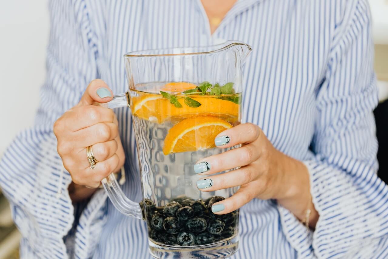 Womans-hands-holding-jar-of-water-with-fruits