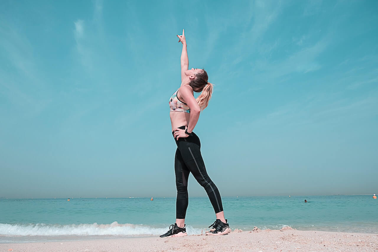 Woman-pointing-at-sky-on-seashore