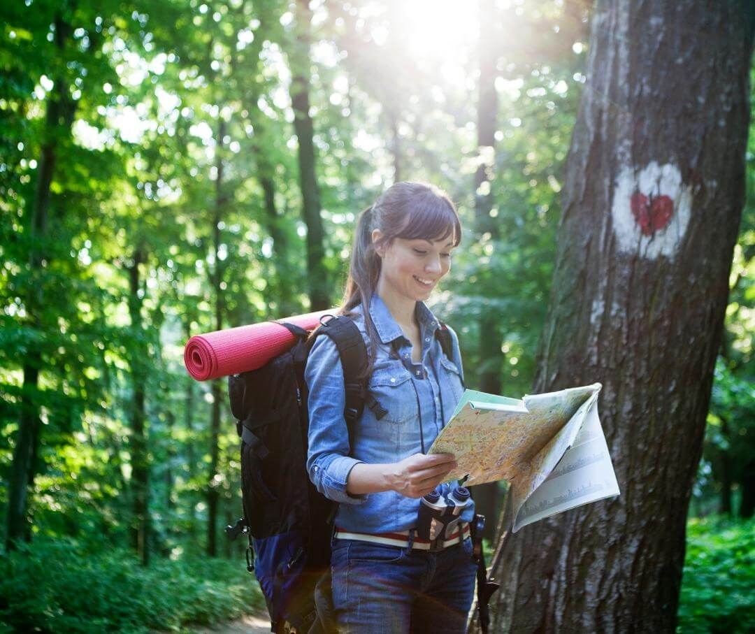 woman backpacking in the woods and holding a map