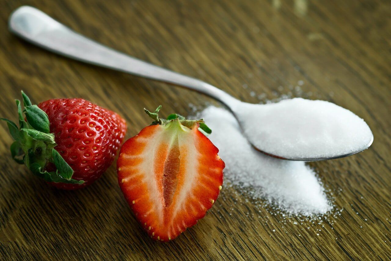 Spoon-full-of-granulated-sugar-and-strawberries-on-the-side