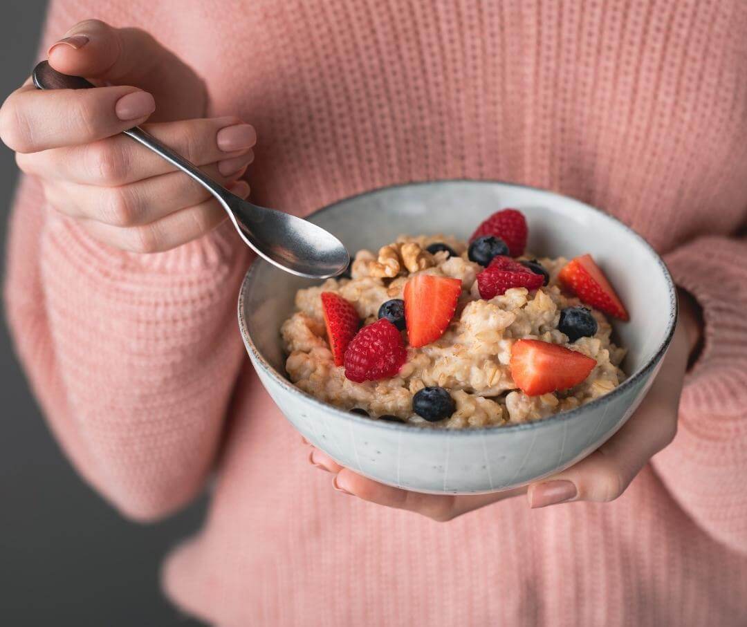 woman holding a bowl of oatmeal with fresh fruit