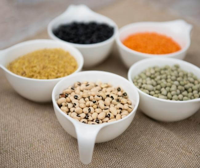 Various legumes sorted into ceramic dishes