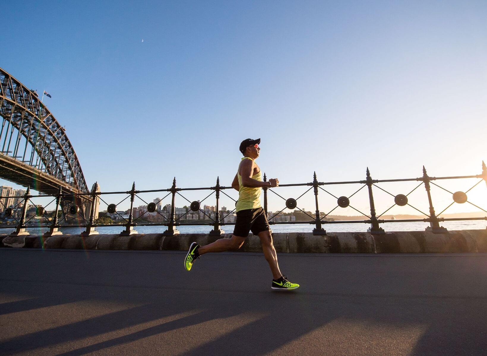 A man running on a paved path with a fence