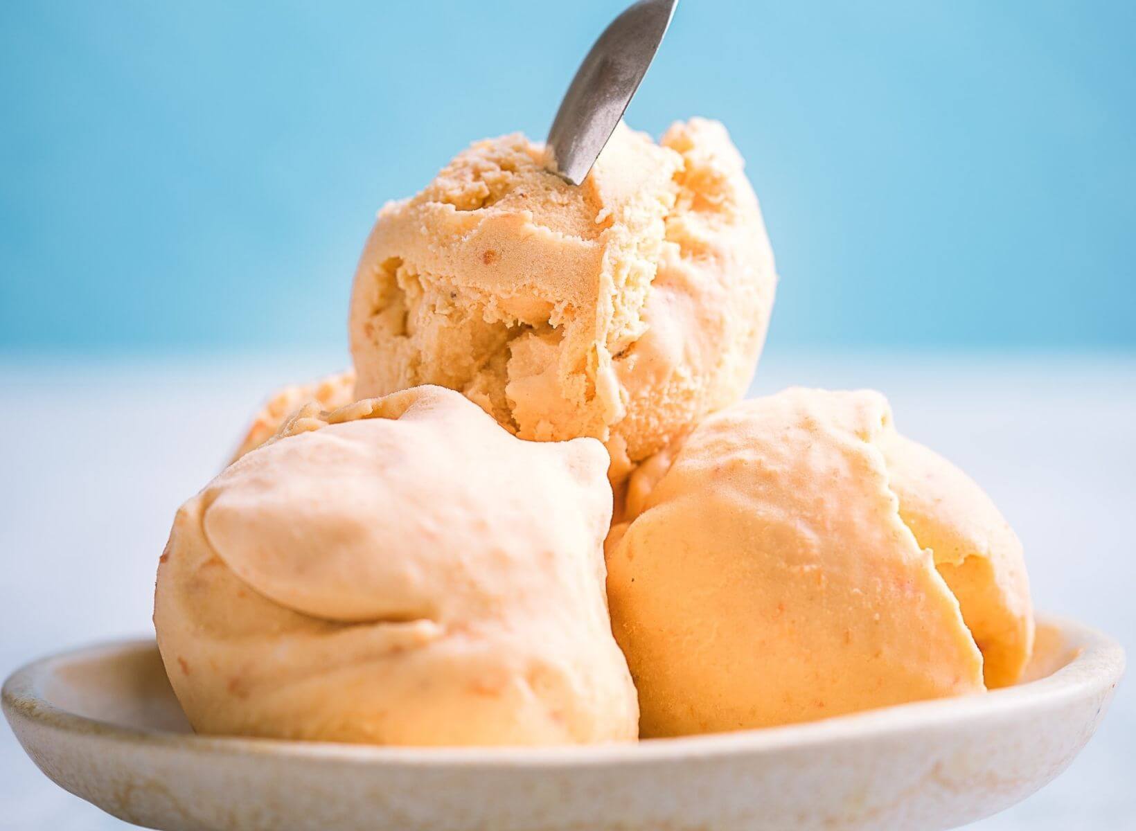 Close up shot of three scoops of vanilla ice cream in a white bowl