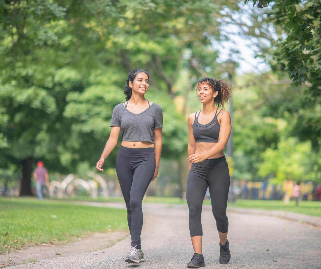 Friends in workout clothes walking in a park.