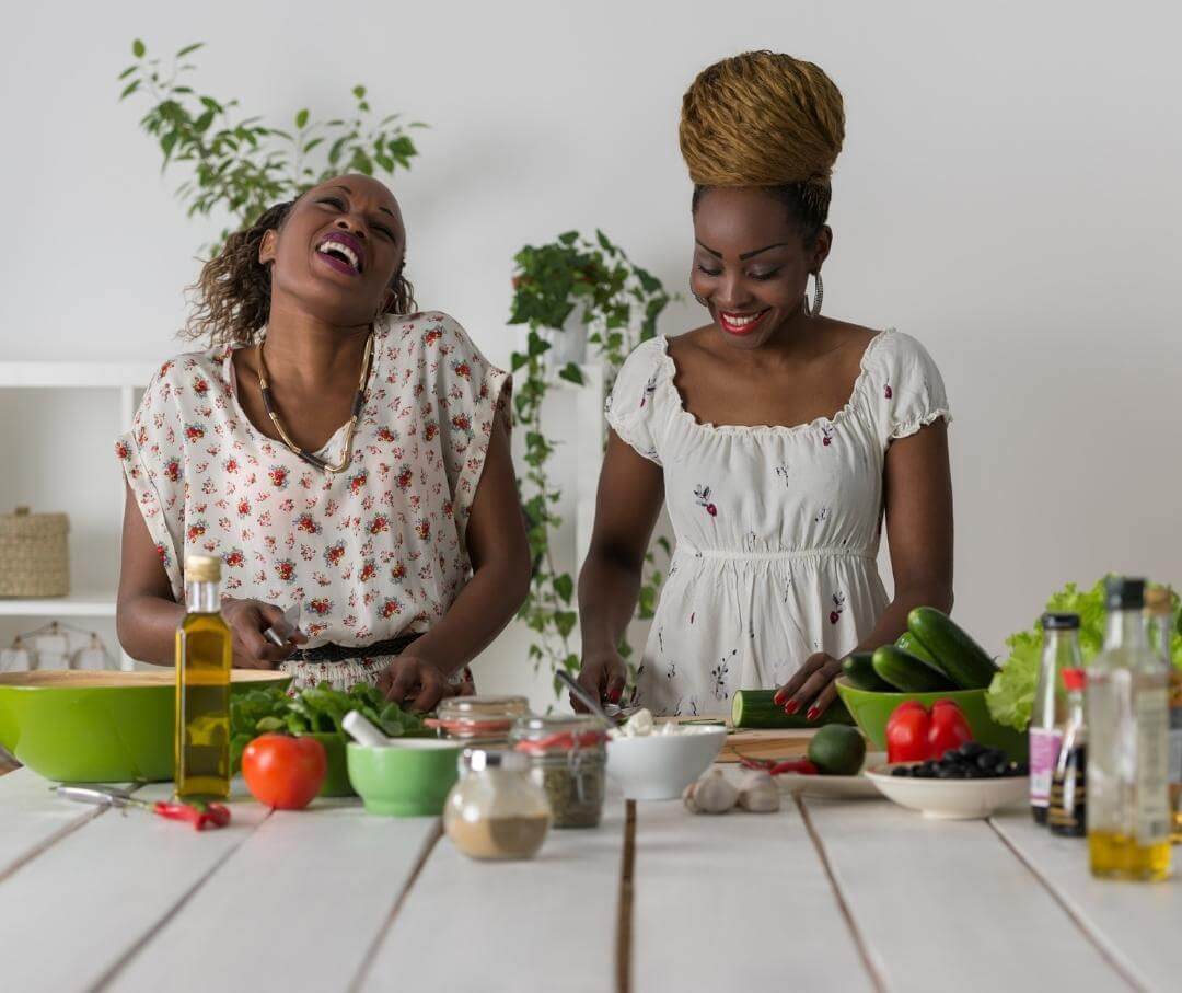 two women smiling and preparing a salad