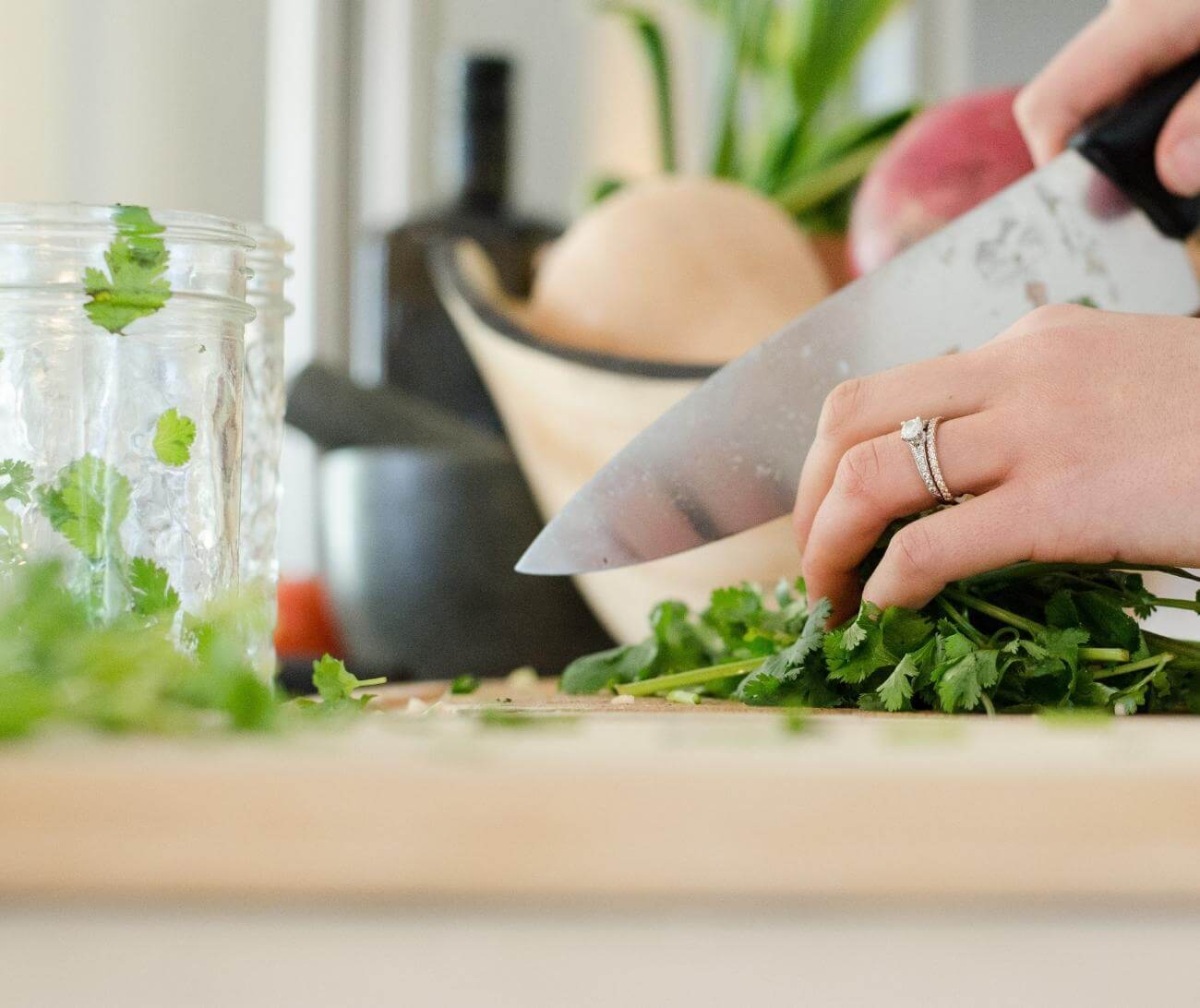 Woman chopping cilantro and putting into a mason jar