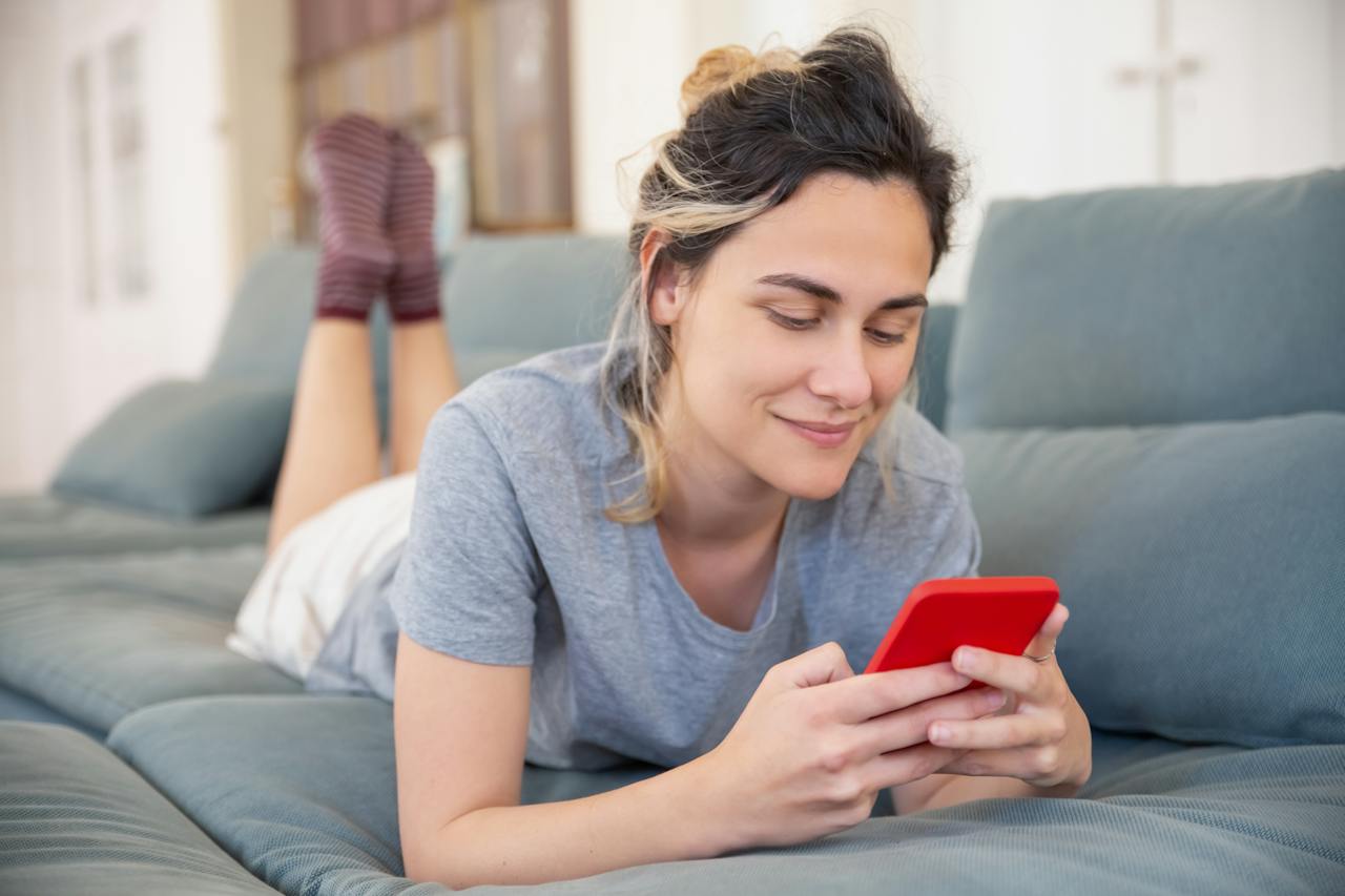 close-up-shot-of-a-woman-lying-on-sofa-while-using-her-cellphone