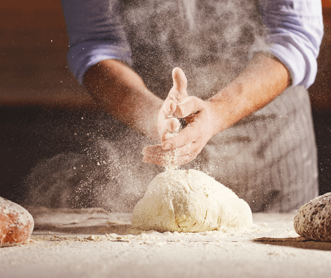 Man powdering bread dough with flour